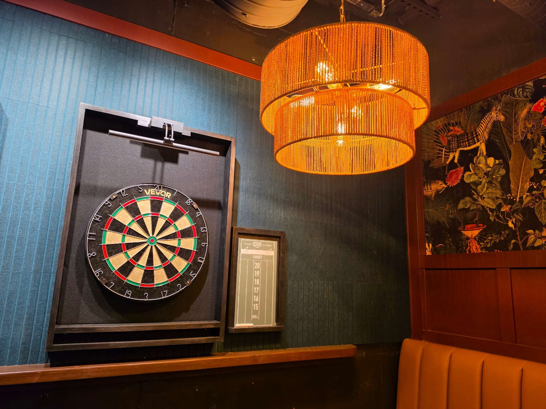 Upstairs dart board next to booth seating and botanical wallpaper