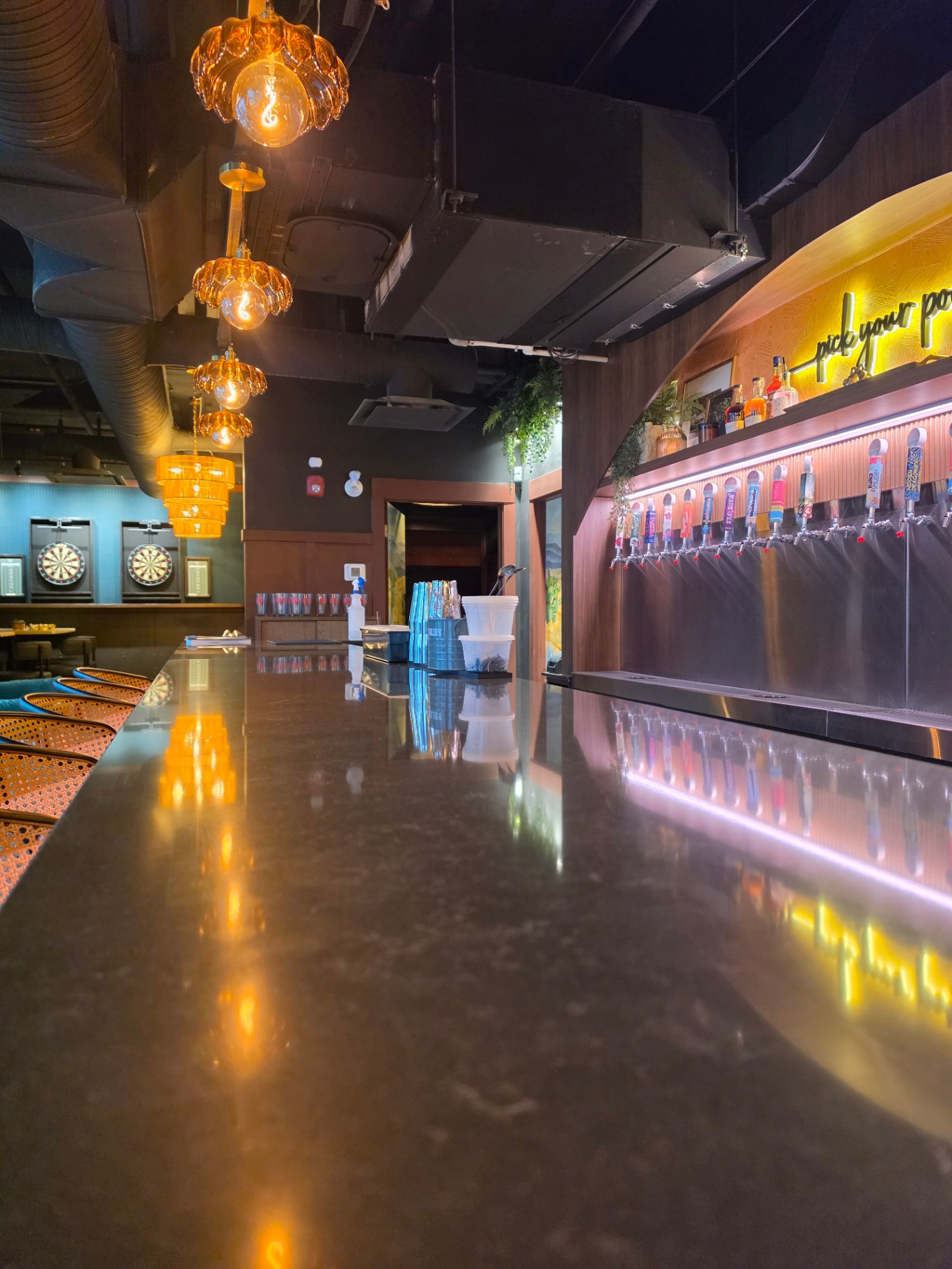 Upstairs bar with amber pendant lights, dart boards, and tap wall